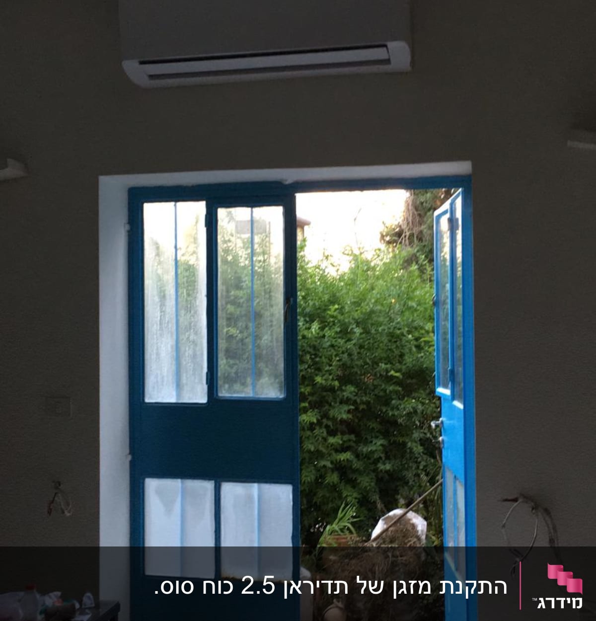 מזגן מותקן מעל דלתות כחולות פתוחות